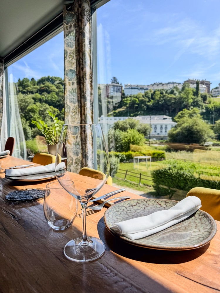 Mesa puesta junto al ventanal de Canedo, con vistas a la vegetación y a la ciudad de Lugo